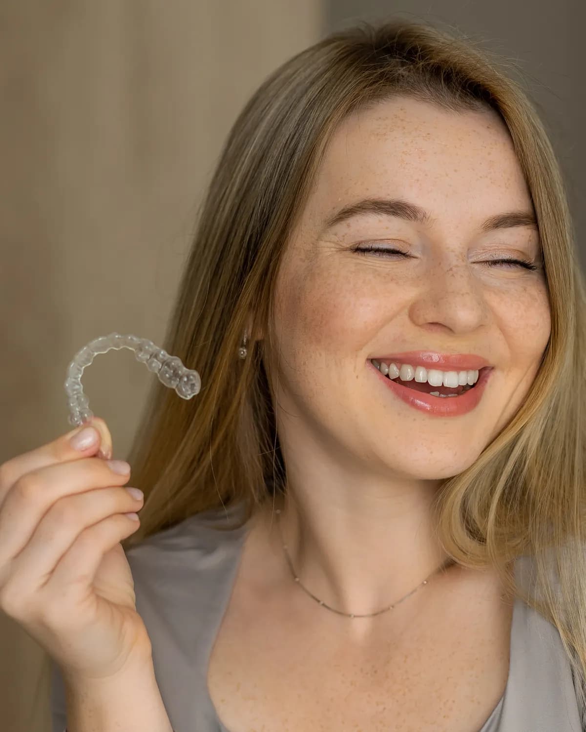 A laughing woman with freckles holding a clear tray